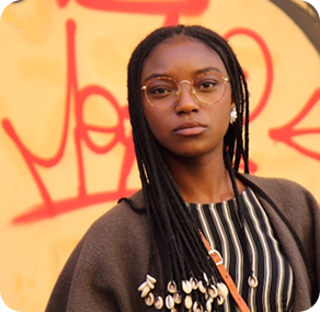 Young woman by a graffiti-covered wall.